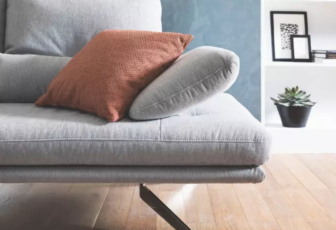 Armteil hellgraues Sofa mit orangenem Kissen